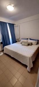 1 dormitorio con 1 cama blanca grande y cortinas azules en Depto. Céntrico en San Salvador de Jujuy