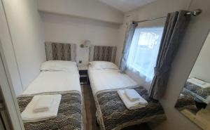 Swarland的住宿－Ash Retreat Hot Tub，一间小房间设有三张床,设有窗户