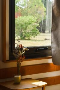 un jarrón con flores sentado en una mesa frente a una ventana en Los Sauces hospedaje rural en Capilla del Señor