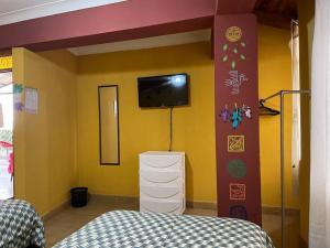 1 dormitorio con 1 cama y TV en la pared en Alojamiento de 2 Habitaciones con Baño Privado en Cuzco
