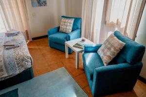 uma sala de estar com duas cadeiras azuis e uma mesa em Casa les Pomeretes em El Figaró