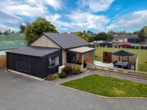 a house with a black roof and a yard at Methven Ski Bach in Methven