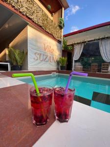 two drinks sitting on a table next to a swimming pool at Suzana Garden in Venus