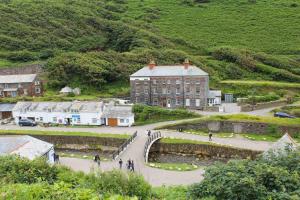 a large building in a village with people walking around it at Bossy Castle in Boscastle