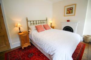 a bedroom with a white bed and a fireplace at Bossy Castle in Boscastle