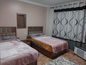 1 dormitorio con 2 camas y ventana en compound city towers elwaha en El Cairo