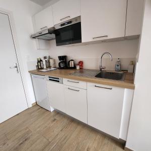 uma cozinha com armários brancos e um lavatório em Héol em Saint Malo