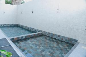 einen Pool mit Fliesenboden und einer weißen Wand in der Unterkunft Appartment Luxe CAPUCINE dans la Zone B Dakar in Fass