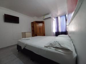 Un dormitorio con una gran cama blanca y una ventana en HOTEL LA FONTANA, en Yopal