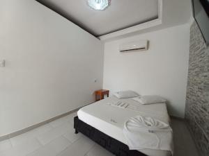 a white bedroom with a bed in a room at HOTEL LA FONTANA in Yopal