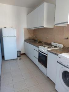 a kitchen with a stove and a white refrigerator at Departamento a 10 metros de la Catedral y plaza principal, con vista desde el balcon in San Fernando del Valle de Catamarca