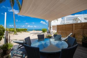 eine Terrasse mit einem Tisch und Stühlen am Strand in der Unterkunft Modern Beach Villa 1150 in Saint Martin