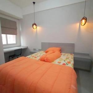 Schlafzimmer mit einem orangenen Bett, einem Schreibtisch und Lampen in der Unterkunft Transpark juanda bekasi in Padurenan