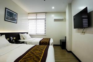 Habitación de hotel con 2 camas y TV de pantalla plana. en PRIMELUXE HOTEL en Cagayán de Oro