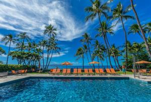 a swimming pool with chairs and palm trees at Wailea Elua by Coldwell Banker Island Vacations in Wailea