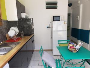 a kitchen with a refrigerator and a table and chairs at ptit coin hibiscus2 in Pointe-Noire