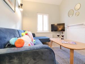 - un salon avec un canapé bleu et une table dans l'établissement Poppy Cottage, à Southwold