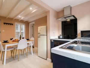 une cuisine avec un évier et une table avec des chaises dans l'établissement Poppy Cottage, à Southwold