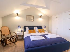 ein Schlafzimmer mit einem blauen Bett und einem Stuhl in der Unterkunft Poppy Cottage in Southwold