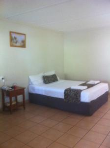 a bedroom with a white bed and white walls at Black Nugget Hotel Motel in Moranbah
