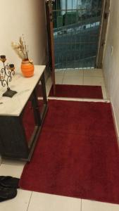 Zimmer mit einem roten Teppich, einem Tisch und einer Tür in der Unterkunft Hostel Palma de Leão in Salvador