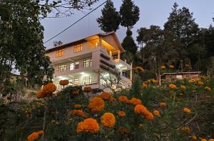 una casa con un campo de flores delante de ella en Bloomfield Farmhouse and Eco-Resort en Darjeeling