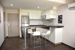 a kitchen with white cabinets and white bar stools at Casa Campus Pilar Suites in Pilar