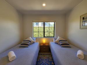 two twin beds in a room with a window at Hahei Garden Sanctuary in Hahei