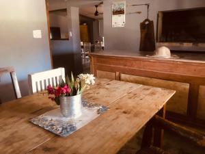 una mesa de madera con un jarrón de flores. en Casa rural familiar con pileta en Arrecifes