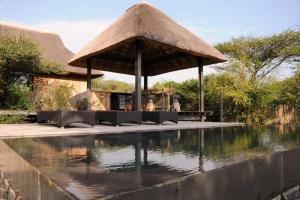 a gazebo with a swimming pool in front of a house at Imvubu Lodge, Royal Jozini PGR, eSwatini in Lavumisa