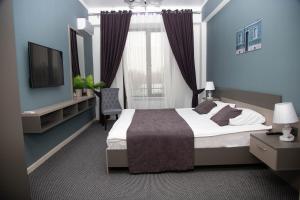 a bedroom with a large bed and a television at Casablanca Apart Hotel in Bishkek