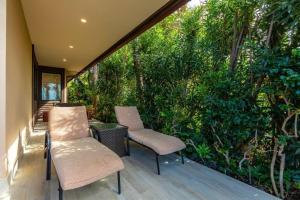 two chairs and a table on a porch with trees at MAKENA SURF, #G-101 condo in Wailea