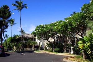 a street in front of a building with palm trees at WAILEA GRAND CHAMPION, #148 condo in Wailea