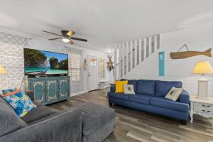 a living room with a blue couch and a tv at Seaside Serenity at Shiplap Shack, Updated Coastal Beach Home w Beach Gear and Idyllic Outdoor Living, Just Steps from the Shore in Panama City Beach