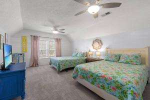 a bedroom with two beds and a flat screen tv at Seaside Serenity at Shiplap Shack, Updated Coastal Beach Home w Beach Gear and Idyllic Outdoor Living, Just Steps from the Shore in Panama City Beach
