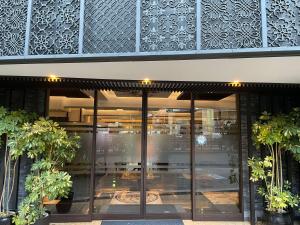 a building with glass doors and plants in front of it at Hotel Kanade Osaka Namba in Osaka