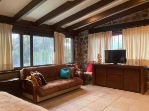 sala de estar con sofá y TV de pantalla plana en Agradable casa rural con piscina privada, en Yautepec