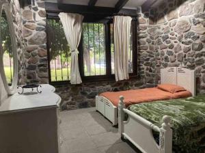 1 dormitorio con 2 camas y pared de piedra en Agradable casa rural con piscina privada, en Yautepec