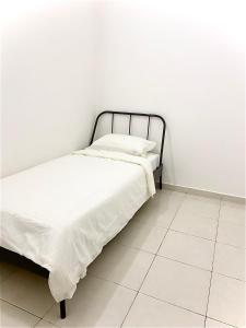 a bed in a room with a white wall at Melur Homestay in Setia Alam