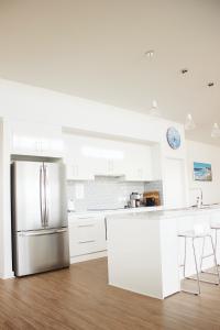 a kitchen with white cabinets and a stainless steel refrigerator at TWO PELICANS Island Beach in Island Beach