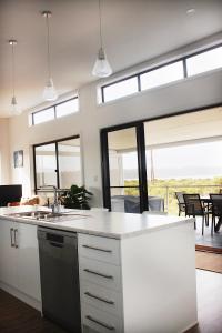 a kitchen with white cabinets and a large window at TWO PELICANS Island Beach in Island Beach