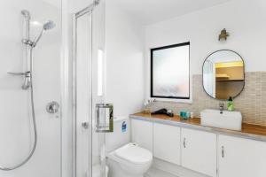 uma casa de banho com um WC, um lavatório e um espelho. em Family Retreat close to City - WiFi Netflix Garden em Auckland