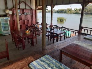 ドン・デトにあるMr. Phaos Riverview Guesthouse & Restaurantのテーブルと椅子が備わる川の景色を望むレストラン