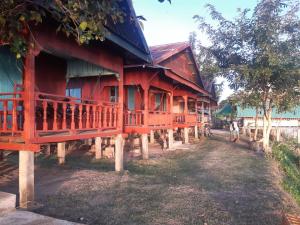 un grupo de casas con madera roja en Mr. Phaos Riverview Guesthouse & Restaurant en Ban Dondét