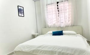 a white bedroom with a bed with a blue pillow at Melur Homestay in Setia Alam