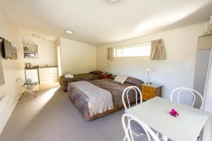 1 dormitorio con 1 cama, mesa y sillas en 10 Cottages en Franz Josef