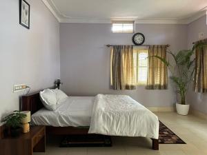 班加羅爾的住宿－Rustic Village Farmhouse，卧室配有一张床,墙上挂着一个钟