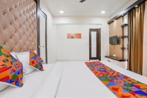 a bedroom with a large bed with a colorful blanket at FabExpress Rudra Residency - Nr Medicover hospital in Chinchiwad