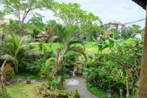 a garden with palm trees and a path at The Gaya in Ubud