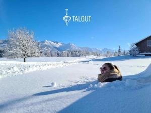 a woman is laying in the snow at Das Talgut in Ofterschwang